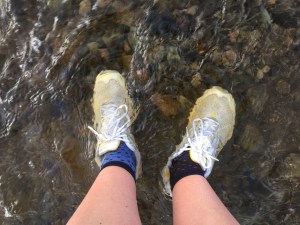 Looking down at feet wearing trainers, submerged in floodwater