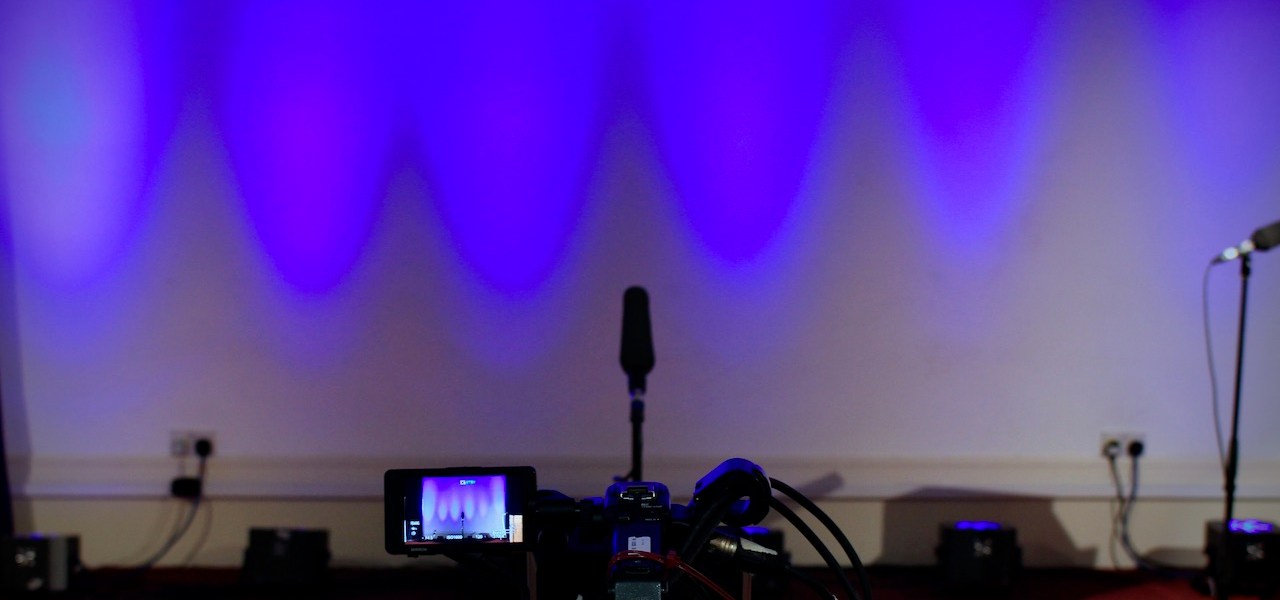 camera pointing at a microphone and blue-lit stage space