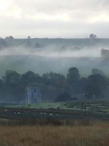 Valley with the ruined tower of Shap Abbey in the bottom, and ground mist rising from the fields